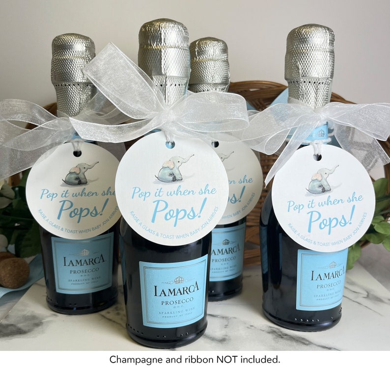 May include: Four mini champagne bottles with white satin ribbon bows and round tags. The tags are white with blue trim and feature a cartoon elephant and the text 'Pop it when she Pops! Raise a glass & toast when baby Jon arrives!'.
Pop It When She Pops Personalized Baby Shower Mini Champagne Bottle Favor Tag Prosecco Elephant Gift Tag Custom Baby Shower Gift Tag