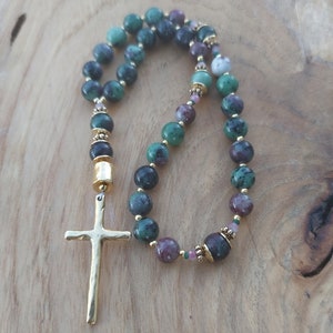 May include: A green and pink gemstone prayer bead mala with a gold cross charm.