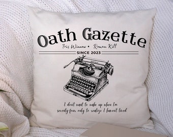 Puede incluir: Una almohada blanca con texto negro que dice "Oath Gazette" con los nombres "Tris Winnow" y "Roman Kitt" y la fecha "SINCE 2023". Una ilustración en blanco y negro de una máquina de escribir vintage está centrada en la almohada. El texto debajo de la máquina de escribir dice "No quiero despertarme cuando tenga 74 años solo para darme cuenta de que no he vivido."