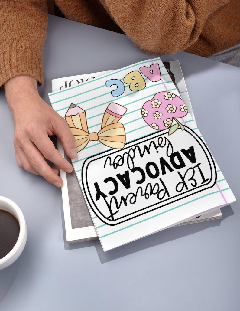 May include: A notebook with a school theme, featuring a pencil and bow illustration, an apple with flowers, and the text "IEP Parent Advocacy". The notebook is open, revealing lined paper with blue lines.