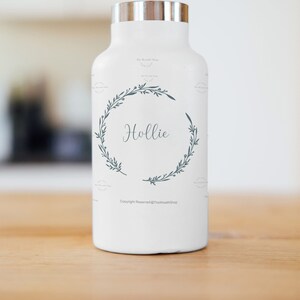 May include: White insulated water bottle with a silver lid and a green floral wreath design. The name "Hollie" is written in the centre of the wreath. The text "Copyright Reserved @TheWreathShop" is printed at the bottom of the bottle.