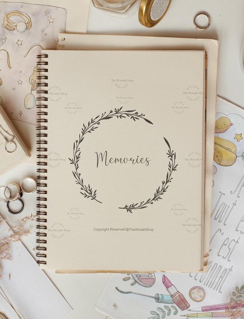 May include: A cream-coloured spiral bound journal with a black wreath design and the word "Memories" in the centre. The journal has the text "Copyright Reserved @TheWreathShop" at the bottom.