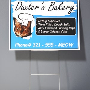 May include: A blue and white sign for Daxter's Bakery, featuring a cat wearing a chef's hat. The sign lists cat-themed treats like catnip cupcakes and tuna-filled dough balls. The phone number is 321-555-MEOW.
