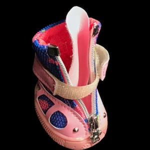 May include: Pink and blue dog boots with a zipper closure and a velcro strap. The boots have a mesh panel and a rubber sole.