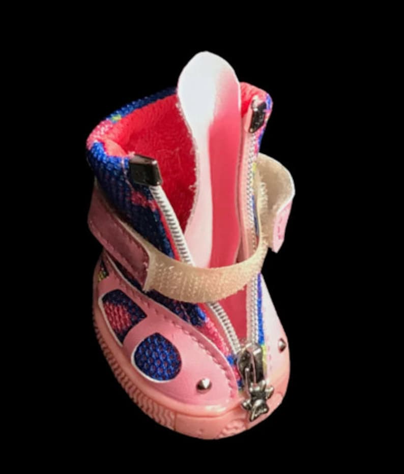 May include: Pink and blue dog boots with a zipper closure and a velcro strap. The boots have a mesh panel and a rubber sole.