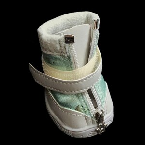 May include: White dog boots with a zipper closure and a green and white patterned lining. The boots have a velcro strap and a JML logo on the side.