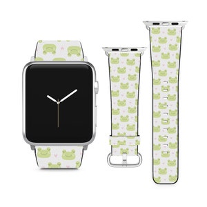 May include: A white Apple Watch with a green and pink frog print band. The watch face is black with white hands and a white second hand.