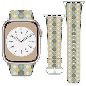 Puede incluir: Un Apple Watch dorado con una esfera blanca y una banda estampada. La banda tiene un patrón geométrico de círculos superpuestos en tonos de verde, azul y beige.
