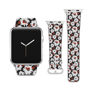 May include: A silver Apple Watch with a white and black daisy and ladybug patterned band. The watch face is black with silver hands.