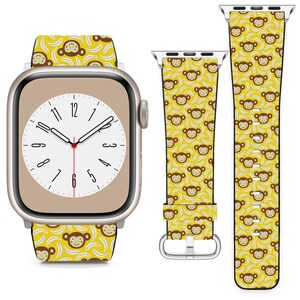 May include: A yellow and brown Apple Watch band with a monkey and banana pattern. The band is shown on a silver Apple Watch with a white watch face.