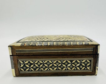 May include: A wooden box with intricate inlaid geometric patterns in shades of brown, black, and white. The box has a hinged lid and is made of wood.