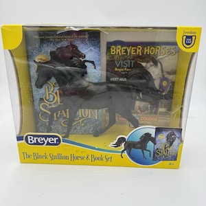 Op de afbeelding: Een Breyer paarden- en boeken set met een zwart paardenbeeldje en twee boeken. De verpakking bevat de tekst "The Black Stallion Horse & Book Set" en "Breyer Horses". De set zit in een doorzichtige plastic doos met een gele rand.