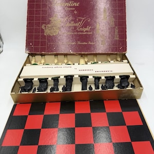 May include: Vintage chess set with a red and black checkered board. The set includes black and cream-colored chess pieces in a box with the text "Florentine Chessmen by Gallant Knight".