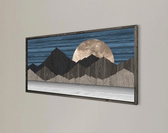 May include: A wood wall art piece with a geometric mountain range design and a large, full moon in the background. The sky is a dark blue with white stripes. The mountains are made of dark wood and the moon is a light brown.