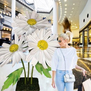 May include: A bouquet of three large white daisies with yellow centers in a shopping mall setting.