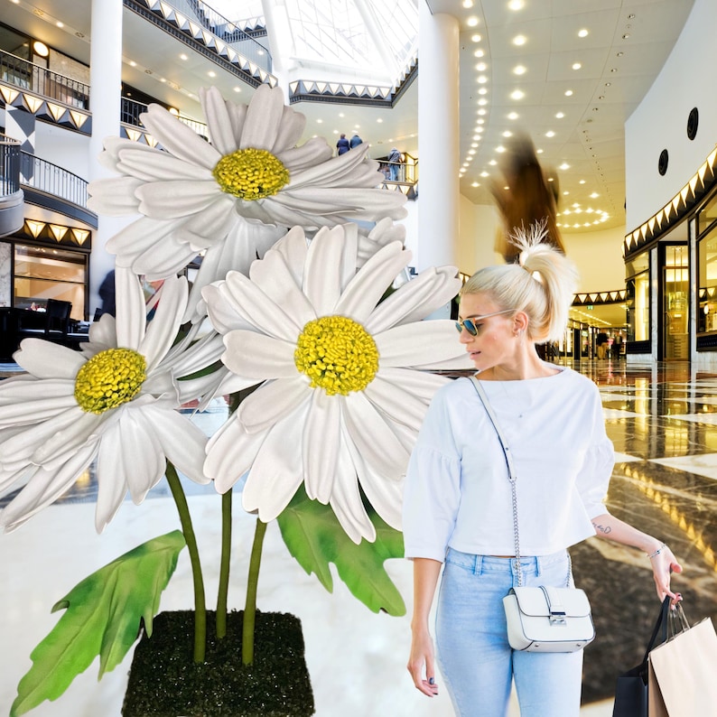 May include: A bouquet of three large white daisies with yellow centers in a shopping mall setting.