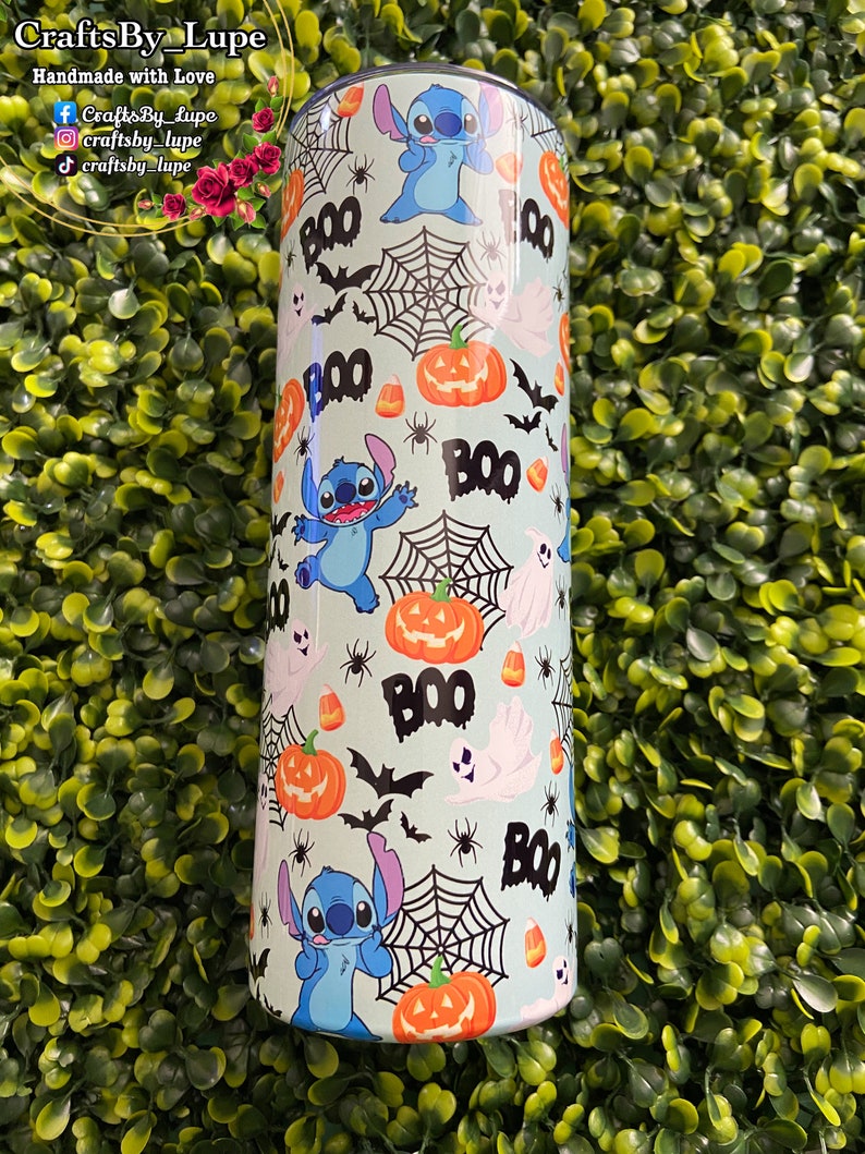 K&ouml;nnte beinhalten: Ein hellblauer Becher mit einem Halloween-Motiv. Das Design zeigt eine blaue Comicfigur, K&uuml;rbisse, Flederm&auml;use, Maisbonbons und Spinnweben. Der Text "BOO" wird im gesamten Design wiederholt.