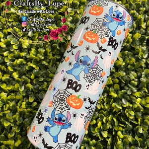 K&ouml;nnte beinhalten: Ein blauer und wei&szlig;er Edelstahlbecher mit Halloween-Motiv. Der Becher zeigt ein sich wiederholendes Muster von Stitch aus Lilo & Stitch, K&uuml;rbissen, Geistern, Flederm&auml;usen, Mais und Spinnweben. Der Text "BOO" erscheint mehrmals auf dem Becher.