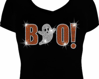 May include: A black V-neck t-shirt featuring a rhinestone graphic on the front. The design displays the word BOO! in orange and white crystals, with a white crystal ghost replacing the letter O. The rhinestones create a sparkling effect.