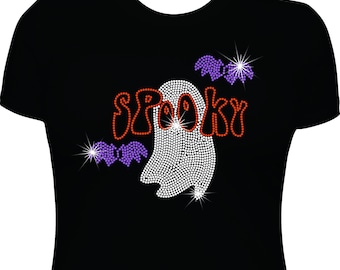 May include: A black short-sleeved t-shirt featuring a rhinestone design on the front. The graphic consists of the word SPOOKY in orange, a white ghost, and two purple bats. The rhinestones create a sparkling effect across the entire design.