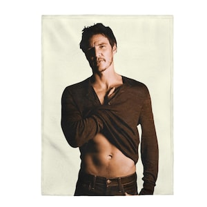 May include: A man wearing a brown long-sleeved shirt, partially unbuttoned to reveal his torso. He is wearing blue jeans and has a serious expression on his face.