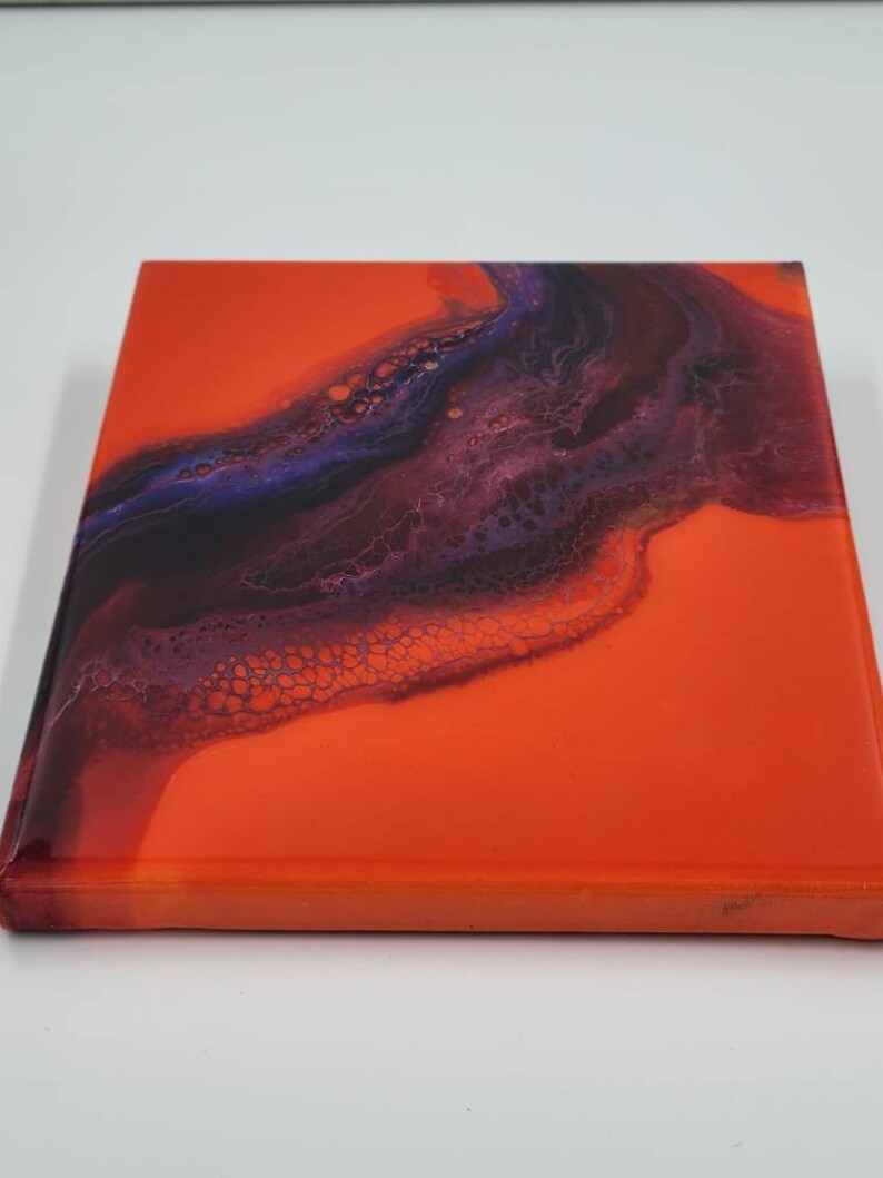 Puede incluir: Pintura abstracta sobre lienzo con un fondo naranja brillante y un dise&ntilde;o de remolino de color morado oscuro y negro.