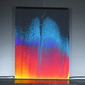 May include: A colourful liquid art piece with a white background. The liquid is layered in shades of blue, purple, red, and orange. The liquid is moving and creating patterns.
