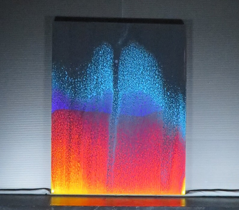 May include: A colourful liquid art piece with a white background. The liquid is layered in shades of blue, purple, red, and orange. The liquid is moving and creating patterns.