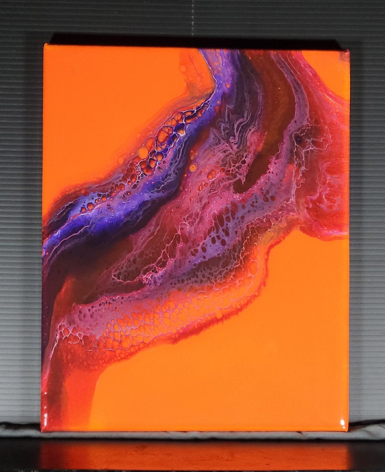 Puede incluir: Pintura abstracta sobre lienzo con un fondo naranja brillante y un patr&oacute;n de pintura p&uacute;rpura, rosa y blanca que se arremolina.
