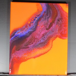 Puede incluir: Pintura abstracta sobre lienzo con un fondo naranja brillante y un patr&oacute;n de pintura p&uacute;rpura, rosa y marr&oacute;n que se arremolina.