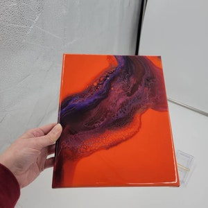 Puede incluir: Pintura abstracta sobre lienzo con un fondo naranja brillante y un dise&ntilde;o de remolino morado y negro.