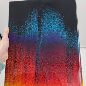 May include: A black background with a colourful abstract design. The design features a gradient of blue, purple, red, and yellow colours. The colours are arranged in a layered effect, creating a sense of depth and dimension.