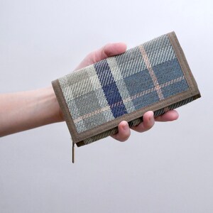 May include: A brown and gray plaid wallet with a zipper closure.