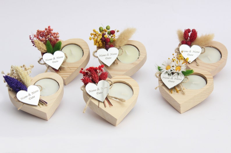 May include: Five wooden heart-shaped candle holders with a small tea light candle in each. Each holder is decorated with dried flowers and a small silver heart tag with the text "Name & Name Date".