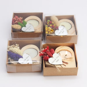 May include: Four small, brown cardboard boxes with clear plastic lids. Each box contains a heart-shaped wooden candle holder with a small white tea light candle. The candle holders are decorated with dried flowers and a small silver heart-shaped tag with the text "Name & Name Date" engraved on it.