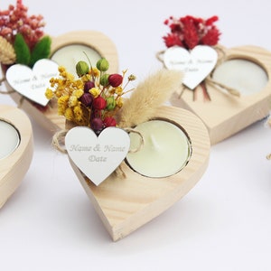 May include: Set of four wooden heart-shaped candle holders with a small tea light candle in each. Each holder is decorated with dried flowers and a silver heart-shaped tag with the text "Name & Name Date".