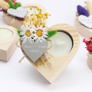 May include: Wooden heart-shaped candle holders with a small tea light candle in each. The holders are decorated with dried flowers and a silver heart tag with the text "Name & Name Date".