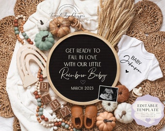 May include: A black letter board with the text "Get ready to fall in love with our little Rainbow Baby March 2023".  The letter board is surrounded by a variety of baby items, including a white onesie with the text "Baby Johnson", a wooden rainbow, a string of wooden beads, and small pumpkins.