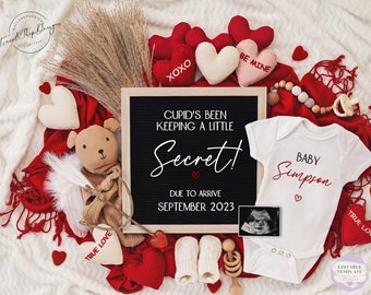 Könnte beinhalten: Eine Valentinstags-Schwangerschaftsanzeige mit einem schwarzen Brett, auf dem steht: "Cupido hat ein kleines Geheimnis gehütet! Ankunft im September 2023". Das Schild ist umgeben von roten Herzen, einem Baby-Strampler mit der Aufschrift "Baby Simpson", einem Teddybär mit Engelsflügeln und einem Pfeil sowie einem Ultraschallbild.