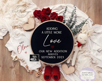 Könnte beinhalten: Ein schwarzes Buchstabenbrett mit dem Text "Adding a little more love. Our new addition arrives September 2023." Ein weißer Strampler mit dem Text "Baby Olsen" in Rot. Eine weiße Decke, rote Rosen, ein Holzhertz, ein Babyrassel, ein Paar rote Babyschuhe und ein gehäkeltes Häschen mit einem roten Herzen.