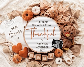 May include: A fall-themed pregnancy announcement with a white onesie that says "Baby Brooks". The announcement includes a letter board with the text "This Year We Are Extra Thankful Arriving November 2027". There are pumpkins, leaves, and a baby ultrasound.
