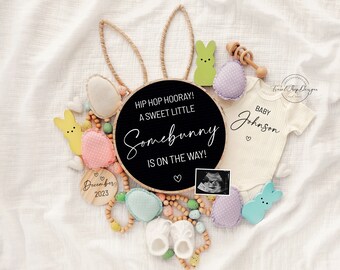 Peut inclure: Une pancarte noire en ardoise avec le texte "Hip Hop Hooray! A Sweet Little Somebunny Is On The Way!" entourée de décorations de Pâques de couleur pastel, y compris des oreilles de lapin, un body de bébé et un hochet en bois.