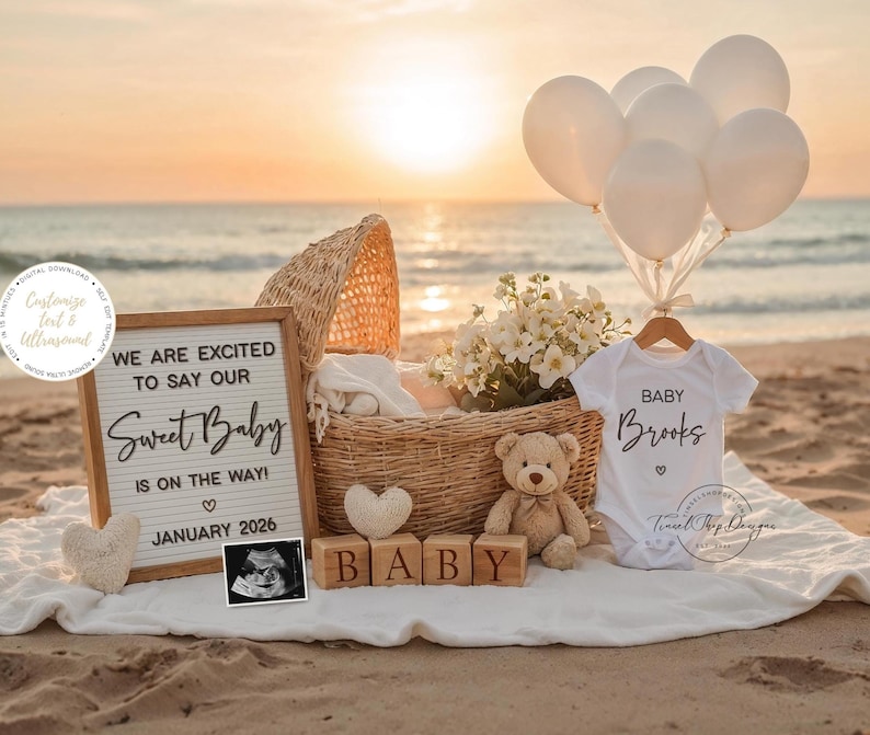 Peut inclure: Sc&egrave;ne de plage avec un panier en osier, des ballons et des v&ecirc;tements de b&eacute;b&eacute;. Une pancarte indique "WE ARE EXCITED TO SAY OUR Sweet Baby IS ON THE WAY! JANUARY 2026." Un body blanc dit "BABY Brooks." Des blocs de bois &eacute;pellent "BABY."