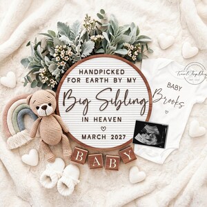 Könnte beinhalten: Ein rundes Buchstabenbrett mit dem Text HANDPICKED FOR EARTH BY MY Big Sibling IN HEAVEN MARCH 2027, ein weißer Babybody mit BABY Brooks, ein beiger Häkelbär, ein Regenbogen in Pastellfarben, weiße Babyschuhe, Holzklötze mit BABY und ein Ultraschallbild.