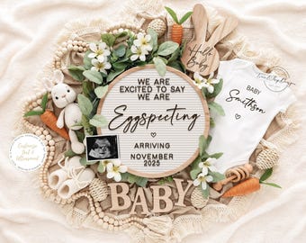 May include: A pregnancy announcement with a white onesie, a letter board with the text "Eggspecting", and a sonogram image. The announcement includes a wooden bunny, carrots, and the text "Hello Baby".