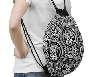 May include: Black and white drawstring backpack featuring a repeating pattern of a tree of life design within a circular frame. The bag has black drawstrings and a black base. The bag is worn over the shoulder.