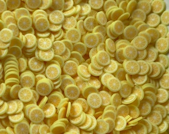 Puede incluir: Una imagen de primer plano de una gran cantidad de adornos en forma de rodajas de limón amarillo. Los adornos están hechos de un material suave y flexible y son perfectos para agregar un toque de verano a las manualidades y los proyectos.