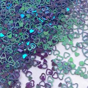 May include: A pile of iridescent blue and green heart-shaped confetti. The confetti is made of a thin, shiny material and has a holographic finish.