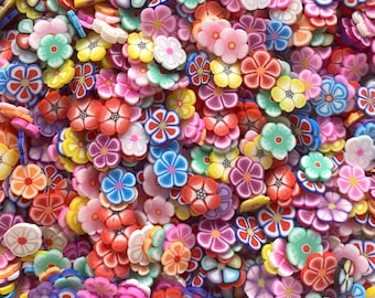 Op de afbeelding: Een grote verzameling kleurrijke polymer clay bloemcharms in verschillende vormen en maten. De charms zijn perfect om een ​​toets van whimsy toe te voegen aan sieraden, knutselwerk en andere projecten.