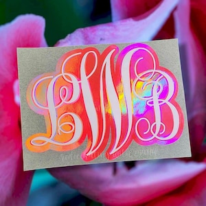 May include: A white monogram sticker with the letters "LWB" in a script font. The sticker is on a silver background and has a holographic finish that shimmers in pink, blue, and yellow.